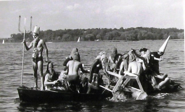 Schergen bringen Neptun und sein Gefolge hier mit einem Tretboot über das Wasser zum Taufplatz (Quelle:Latte)
